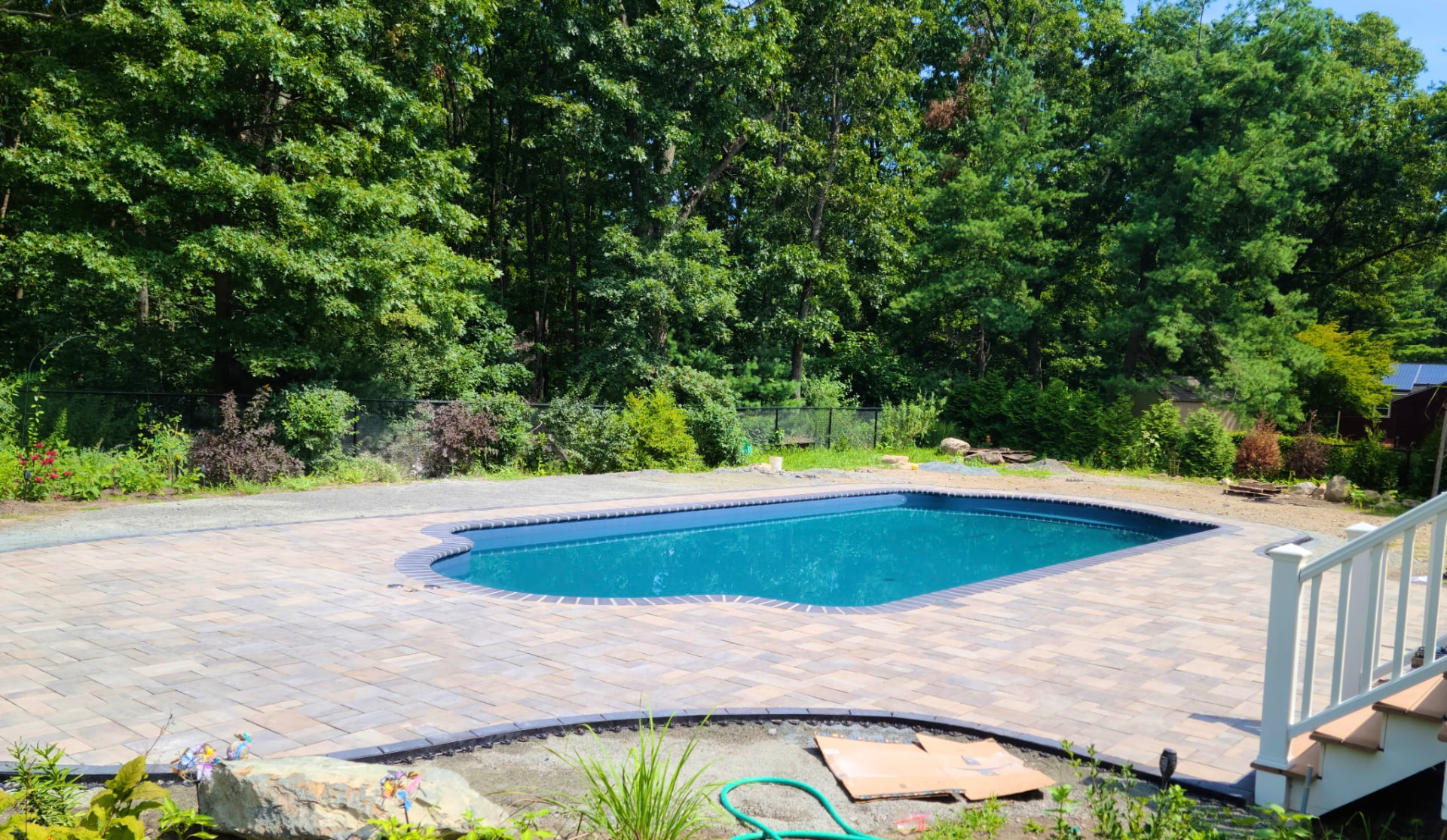 Completed DoMore Outdoors project: paver pool patio surrounding an in-ground pool