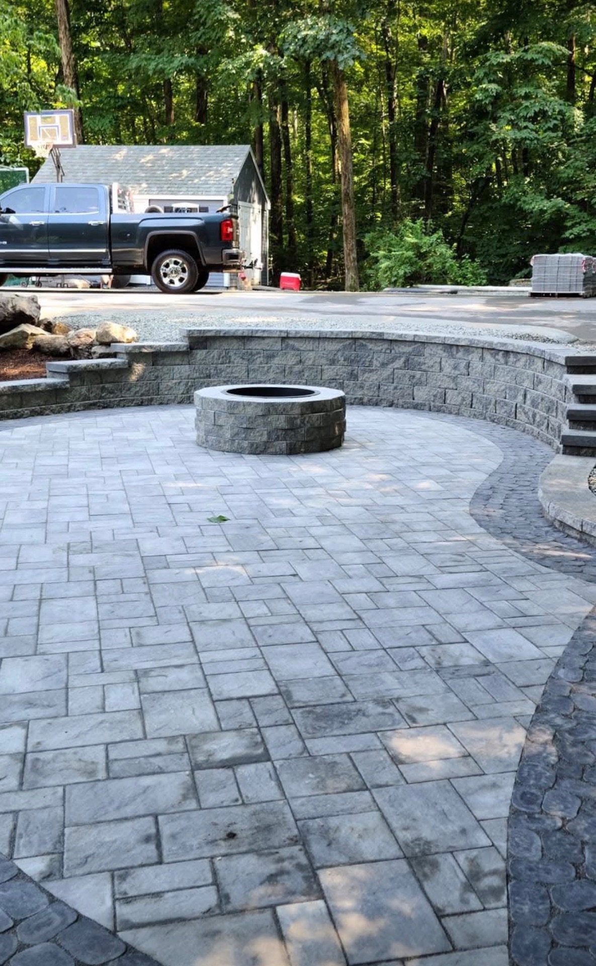 Custom stone patio with curved fire pit and paver design